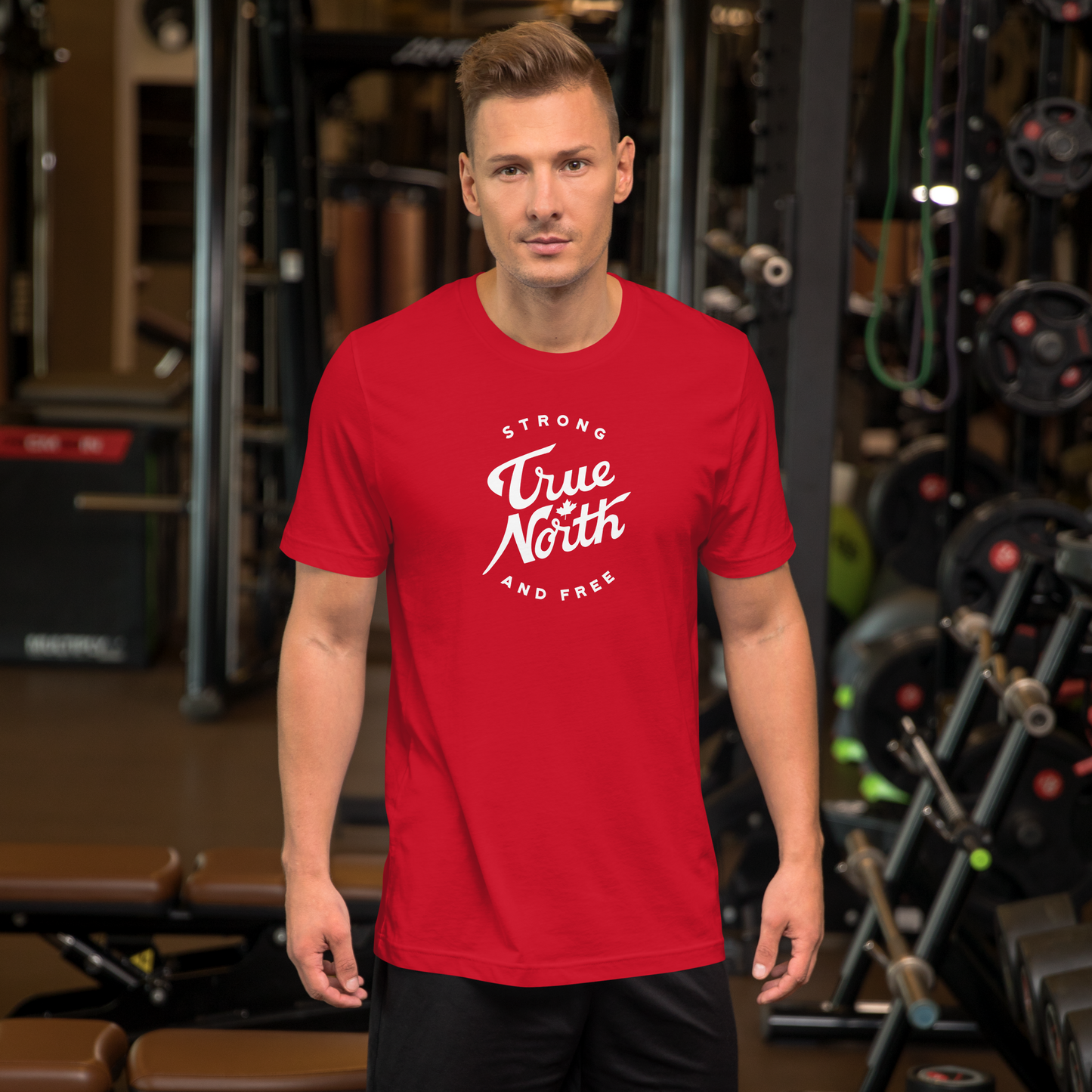 Man wearing a red t-shirt with 'True North Strong and Free' text in a gym setting